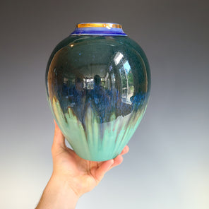 A navy and teal porcelain vessel with a dark blue and gold luster neck.