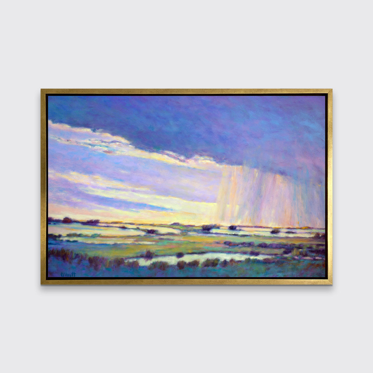 A blue, purple and yellow abstract landscape print in a gold floater frame hangs on a white wall.