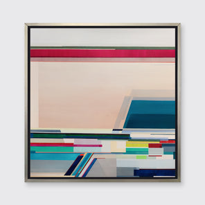 A multi-colored geometric print in a silver floater frame hangs on a white wall.