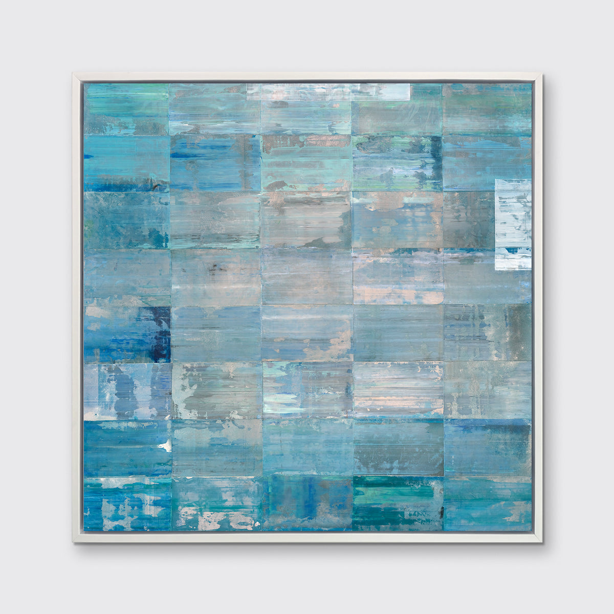 A blue, teal and silver geometric abstract print in a white floater frame hangs on a white wall.