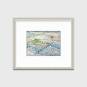 A brown, grey and light green abstract landscape print in a silver frame with a mat hangs on a white wall.