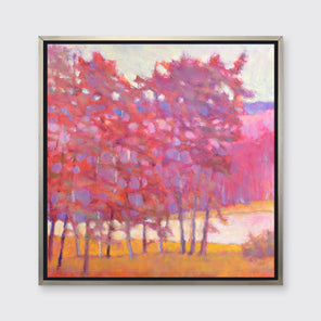 A red and pink tree landscape print in a silver floater frame hangs on a white wall.
