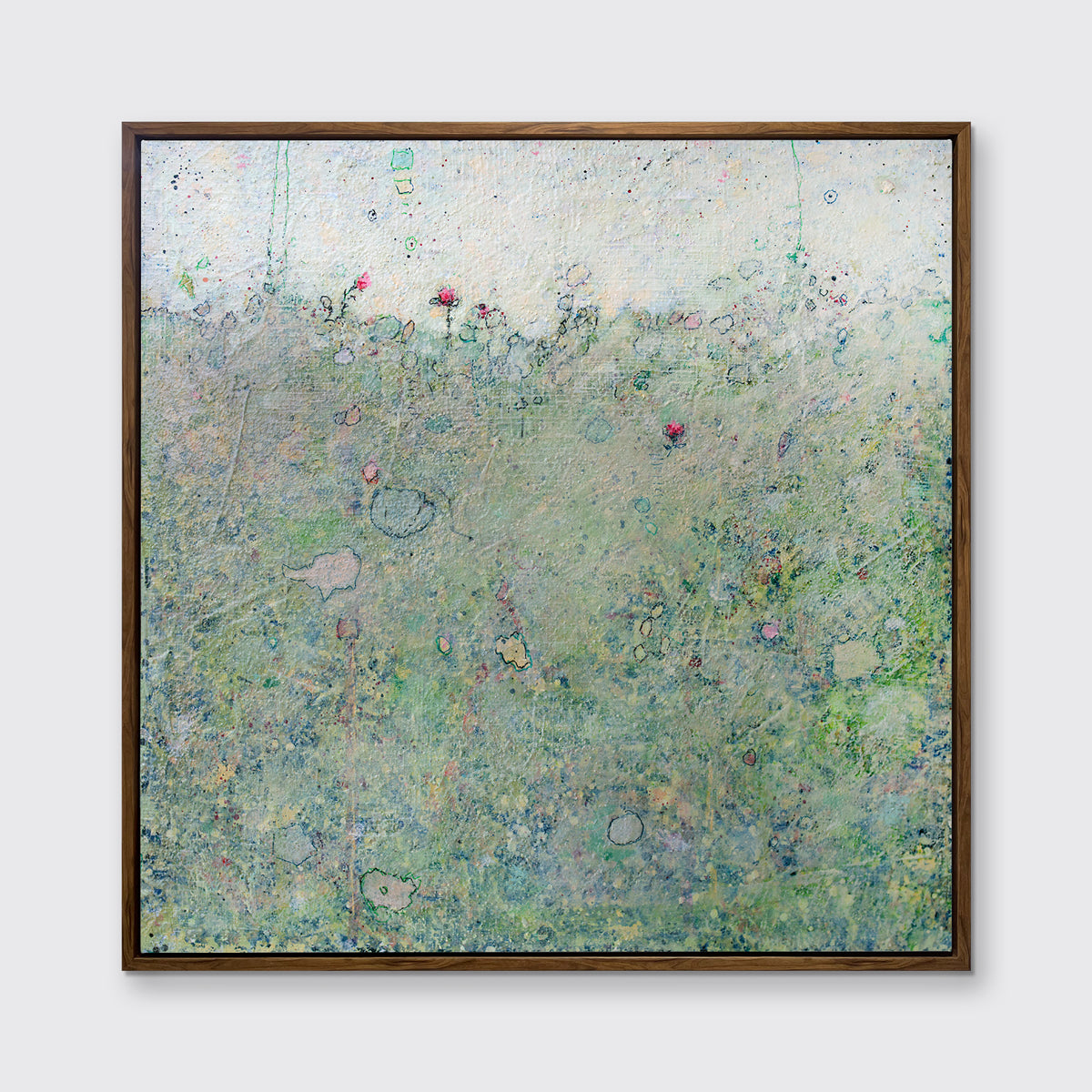 A green abstract landscape print in an oak wood floater frame hangs on a white wall.