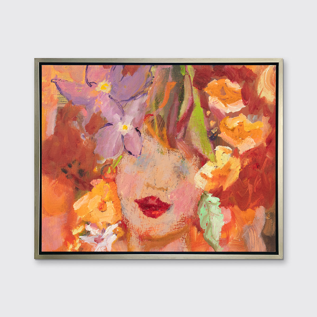 A red, orange, yellow and purple figural print in a silver floater frame hangs on a white wall.