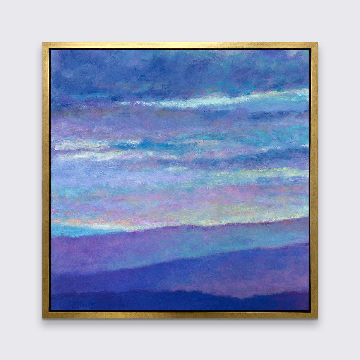 A blue, purple and light yellow abstract landscape print in a gold floater frame hangs on a white wall.