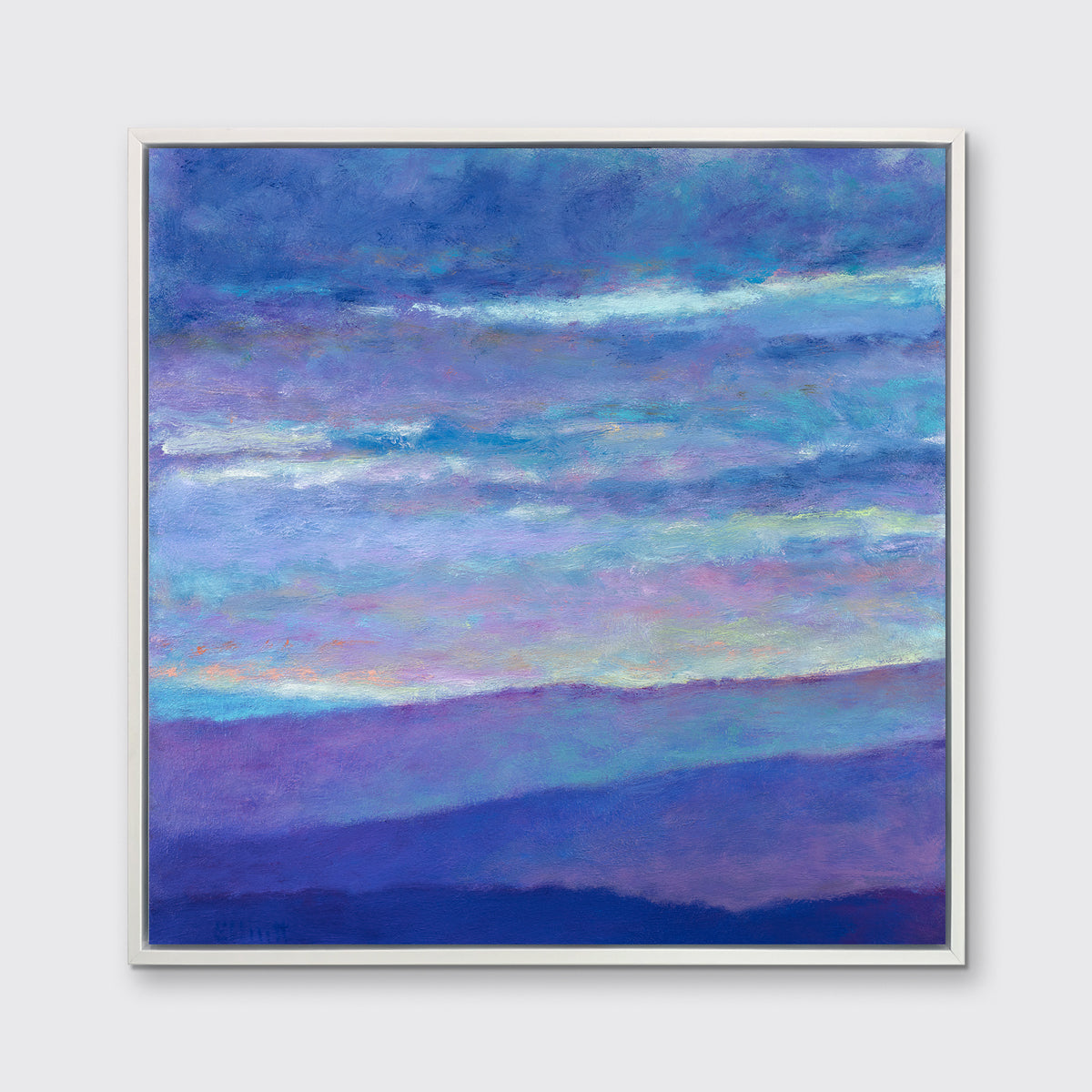 A blue, purple and light yellow abstract landscape print in a white floater frame hangs on a white wall.