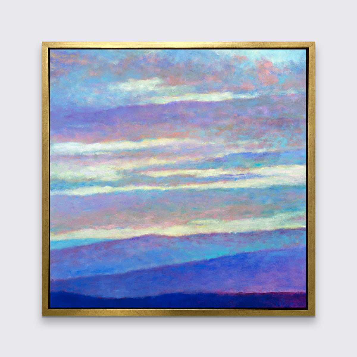 A blue, purple and light yellow abstract landscape print in a gold floater frame hangs on a white wall.