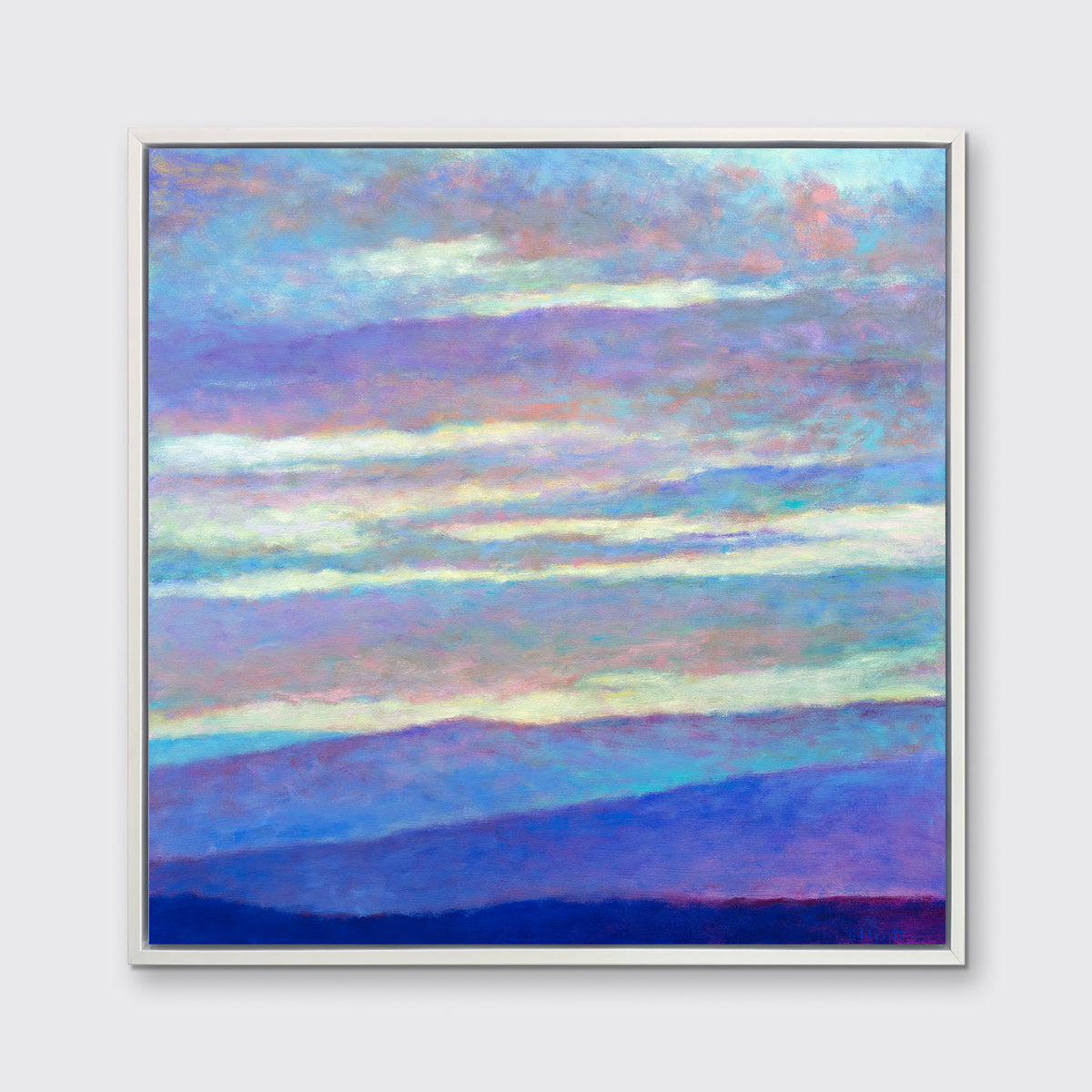 A blue, purple and light yellow abstract landscape print in a white floater frame hangs on a white wall.
