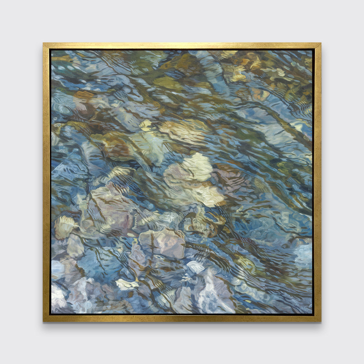 An abstract river bed print in a gold floater frame hangs on a white wall.