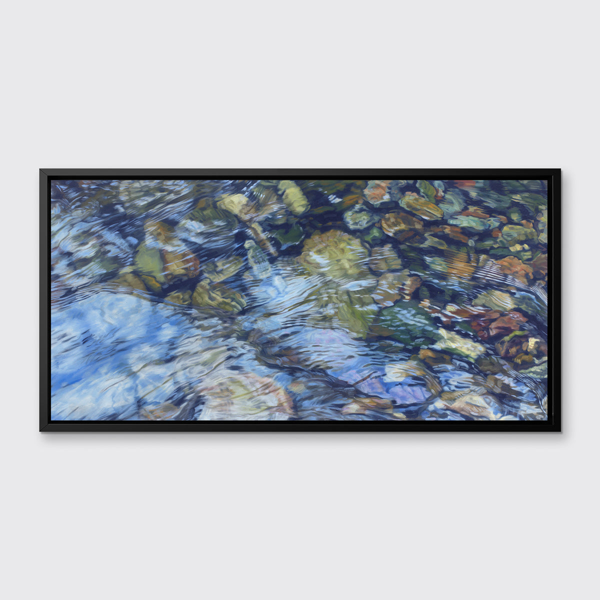 An abstract riverbed print in a black floater frame hangs on a white wall.