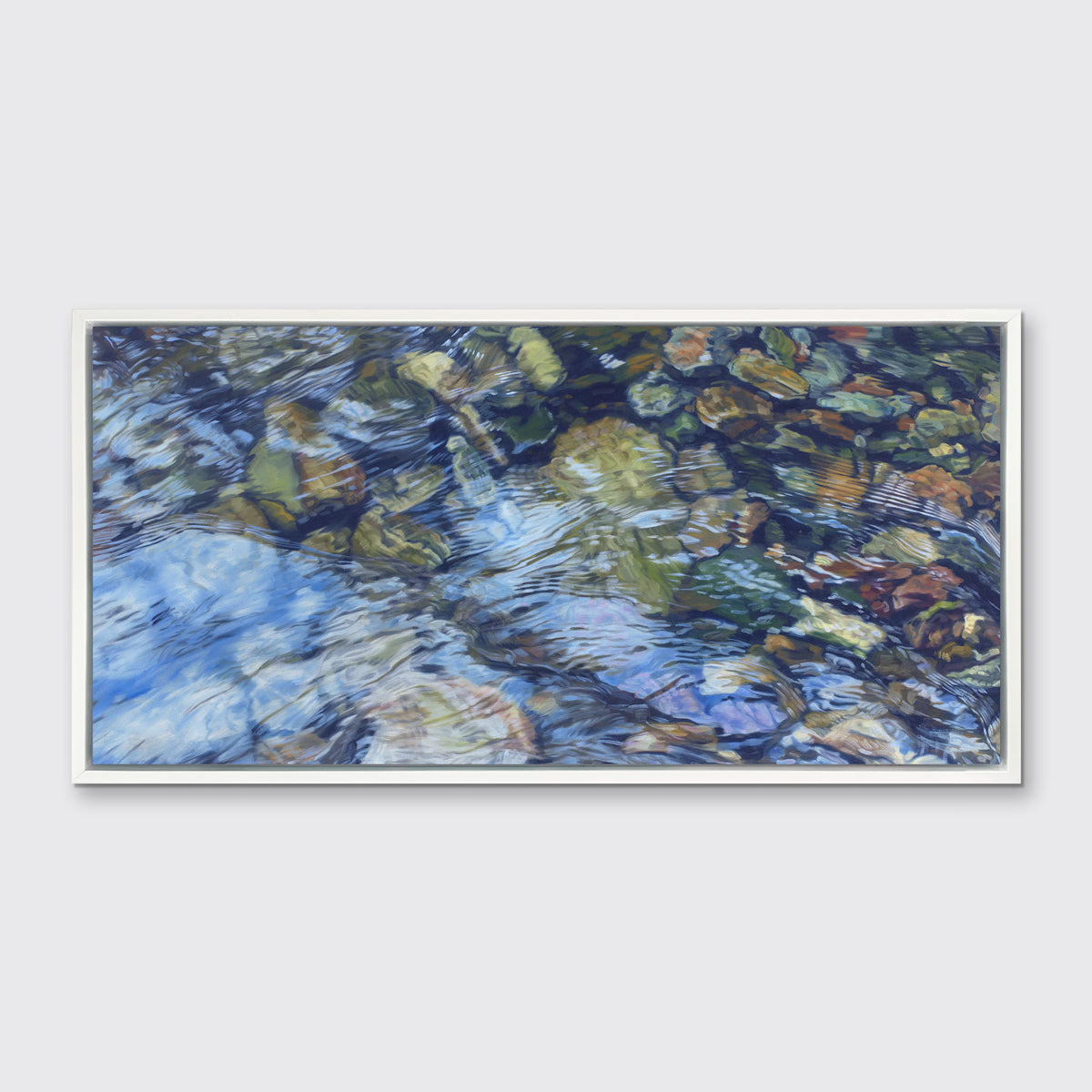 An abstracted riverbed print in a white floater frame hangs on a white wall.