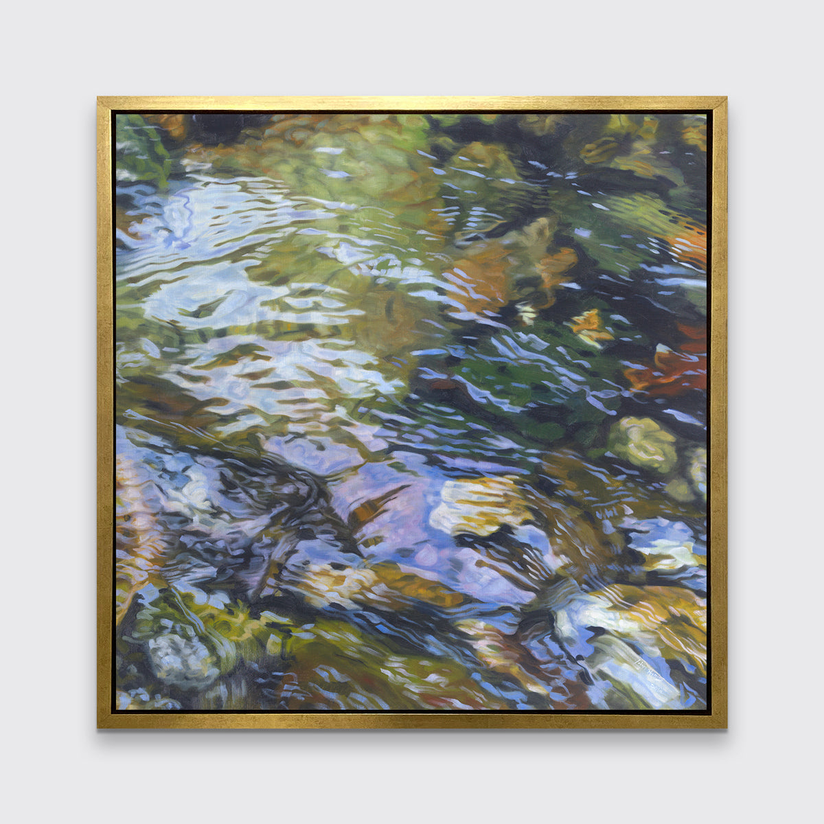A green, brown and beige abstract river rock in water print in a gold floater frame hangs on a white wall.