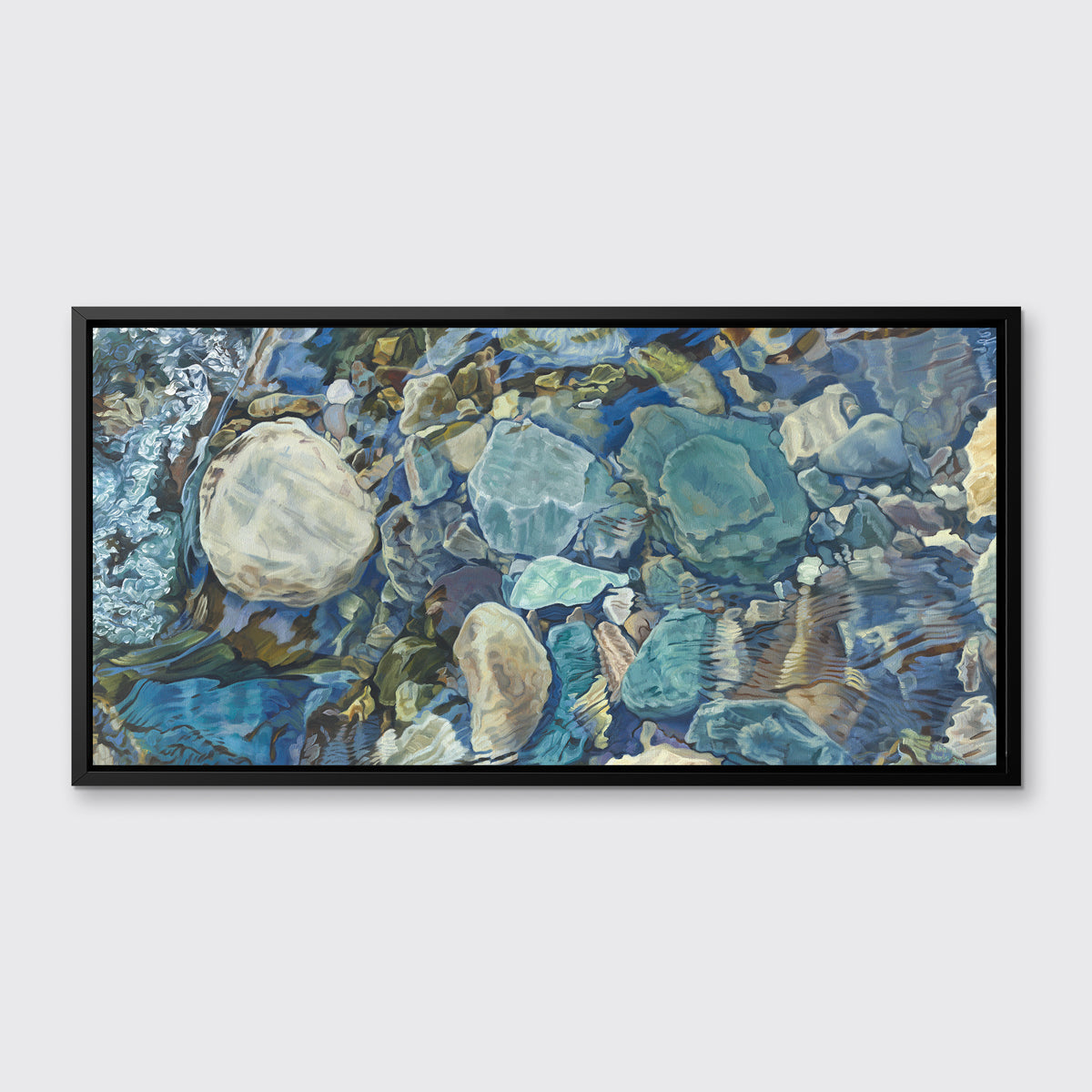 Abstracted print of grey, brown, green and beige river rocks under water hangs in a black floater frame on a white wall.