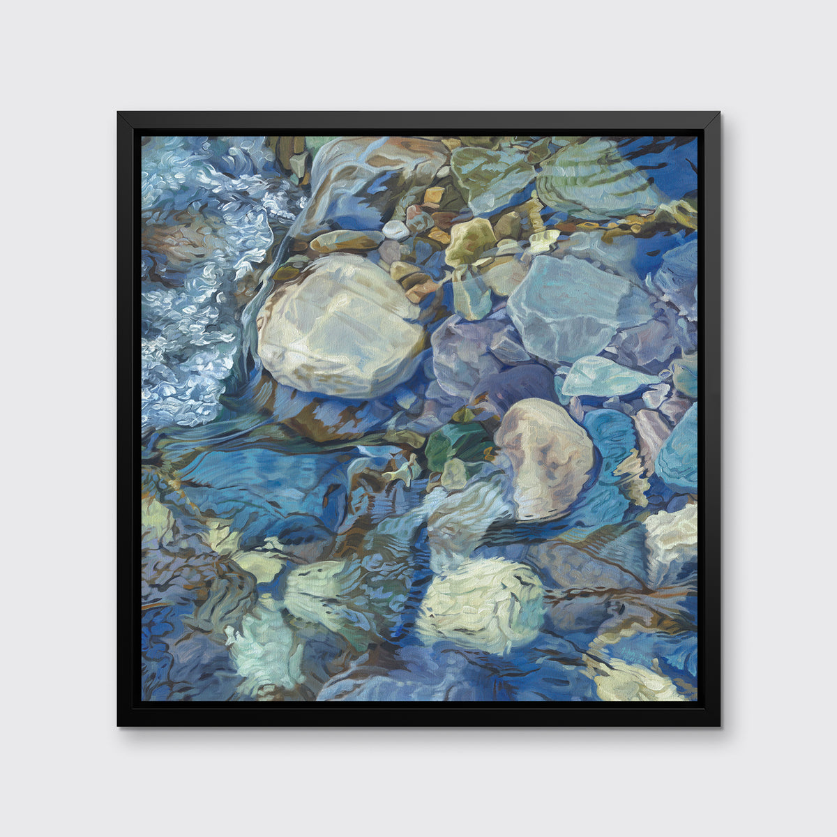 Abstracted print of grey, brown, green and blue river rocks under water hangs in a black floater frame on a white wall.