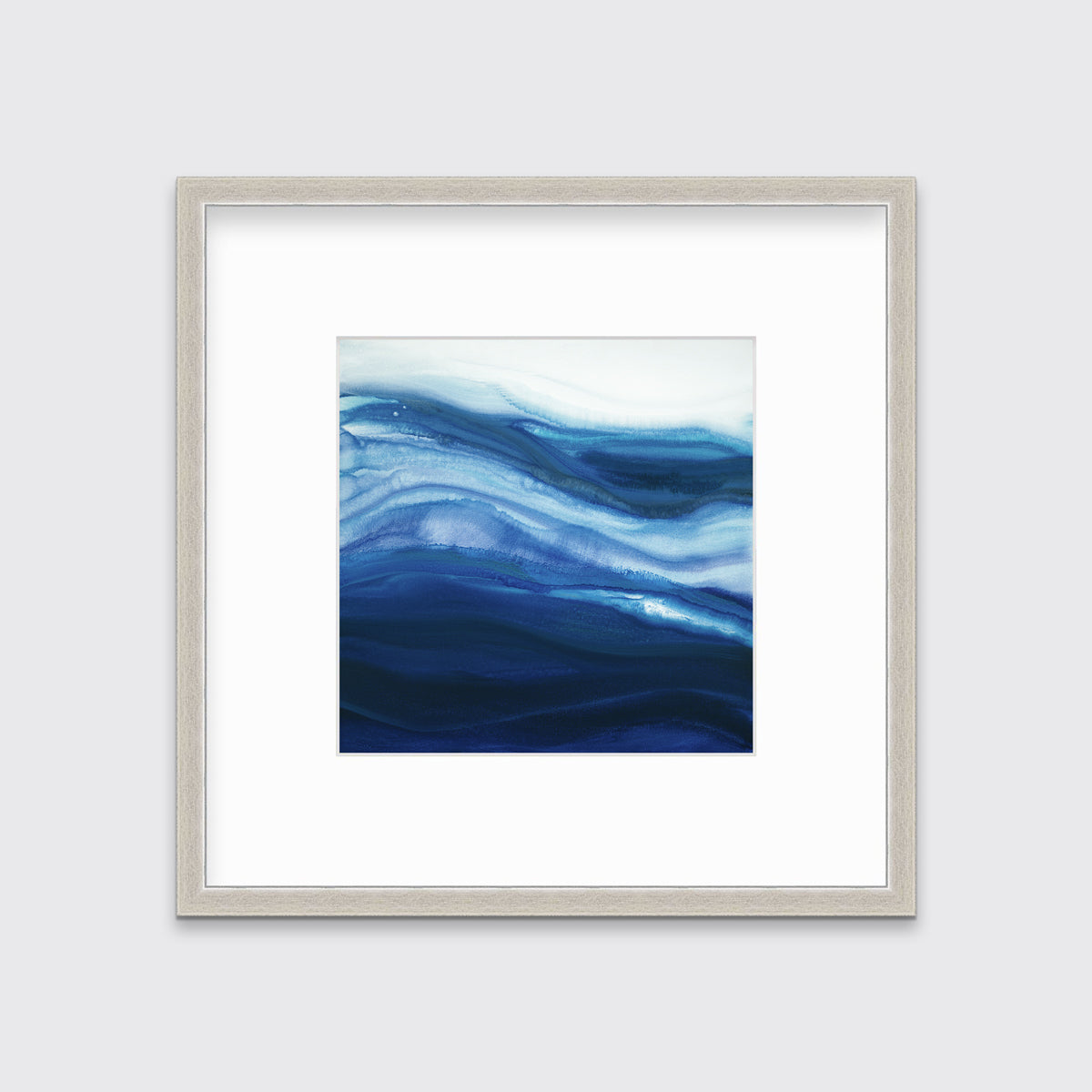 A blue, teal and white abstract print in a silver frame with a mat hangs on a white wall.