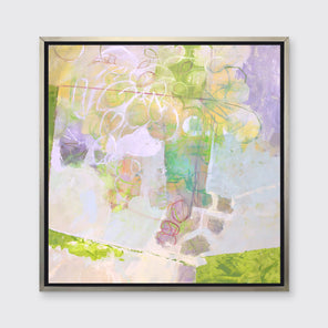 A light yellow, lavender and green abstract floral print in a silver floater frame hangs on a white wall.