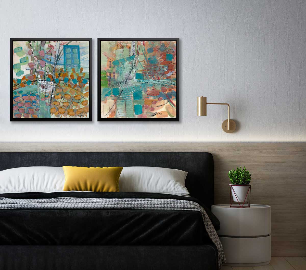 Two abstract prints in black floater frames hang next to a gold wall lamp above a modern bed with black, white, and yellow linens and a modern end table with a potted plant.