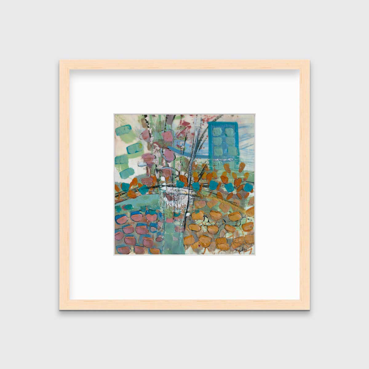 A multicolored abstract print, matted and framed in a natural wood frame hangs on a grey wall.