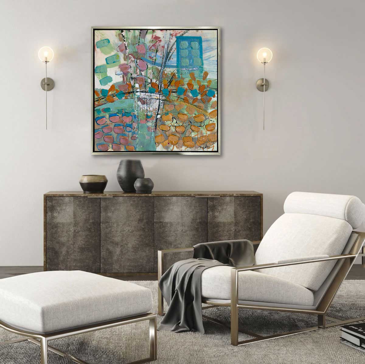 A multicolored abstract print framed in a gold floater frame hangs on a grey wall between two modern sconces, and above a dark console table and modern reclining chair and chaise.