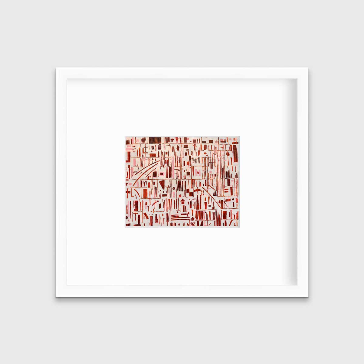 A red, pink and white abstract print in a white frame with a mat hangs on a white wall.