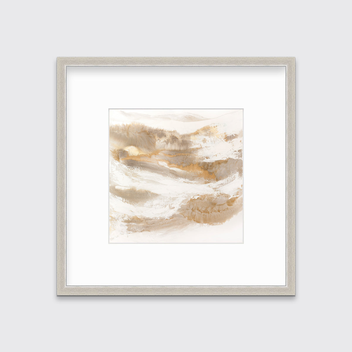 A gold, silver, white and beige abstract print in a silver frame with a mat hangs on a white wall.
