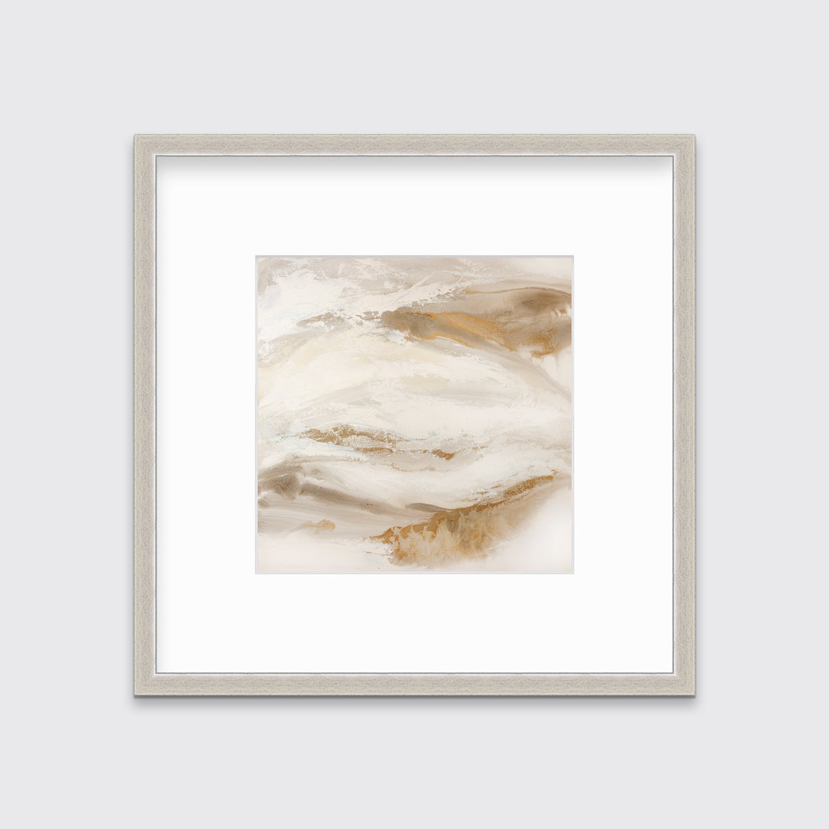 A gold, silver, white and beige abstract print in a silver frame with a mat hangs on a white wall.