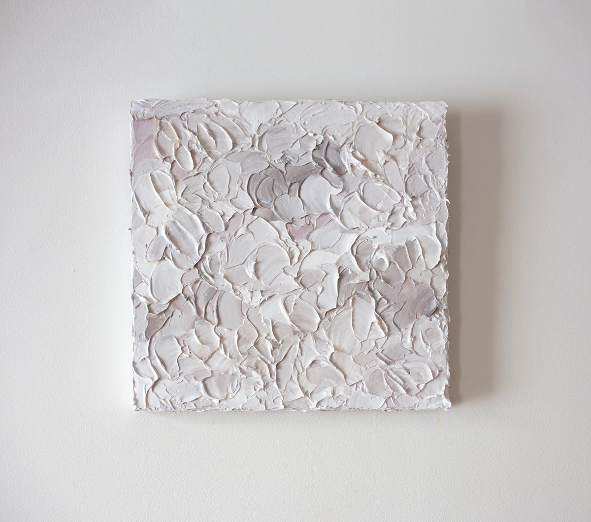 A light pink, white and warm grey impasto abstract painting. Hangs on a white gallery wall. 