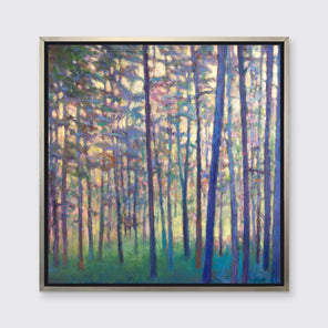 A colorful tree landscape print in a silver floater frame hangs on a white wall.