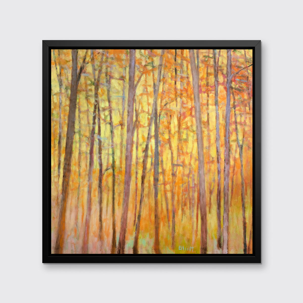 A yellow and orange impressionistic forest print in a black floater frame hung on a light grey wall.