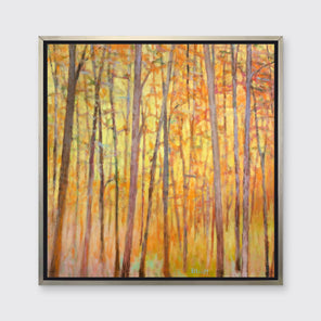 A yellow and orange impressionistic forest print in a silver floater frame hung on a light grey wall.