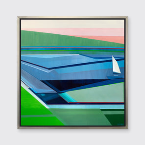 A green, blue and light pink geometric abstract seascape print with a sailboat in a silver floater frame hangs on a white wall.