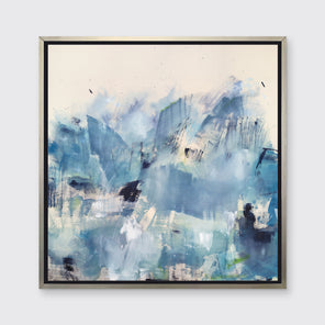 A blue and white abstract print framed in a silver frame hangs on a white wall. 