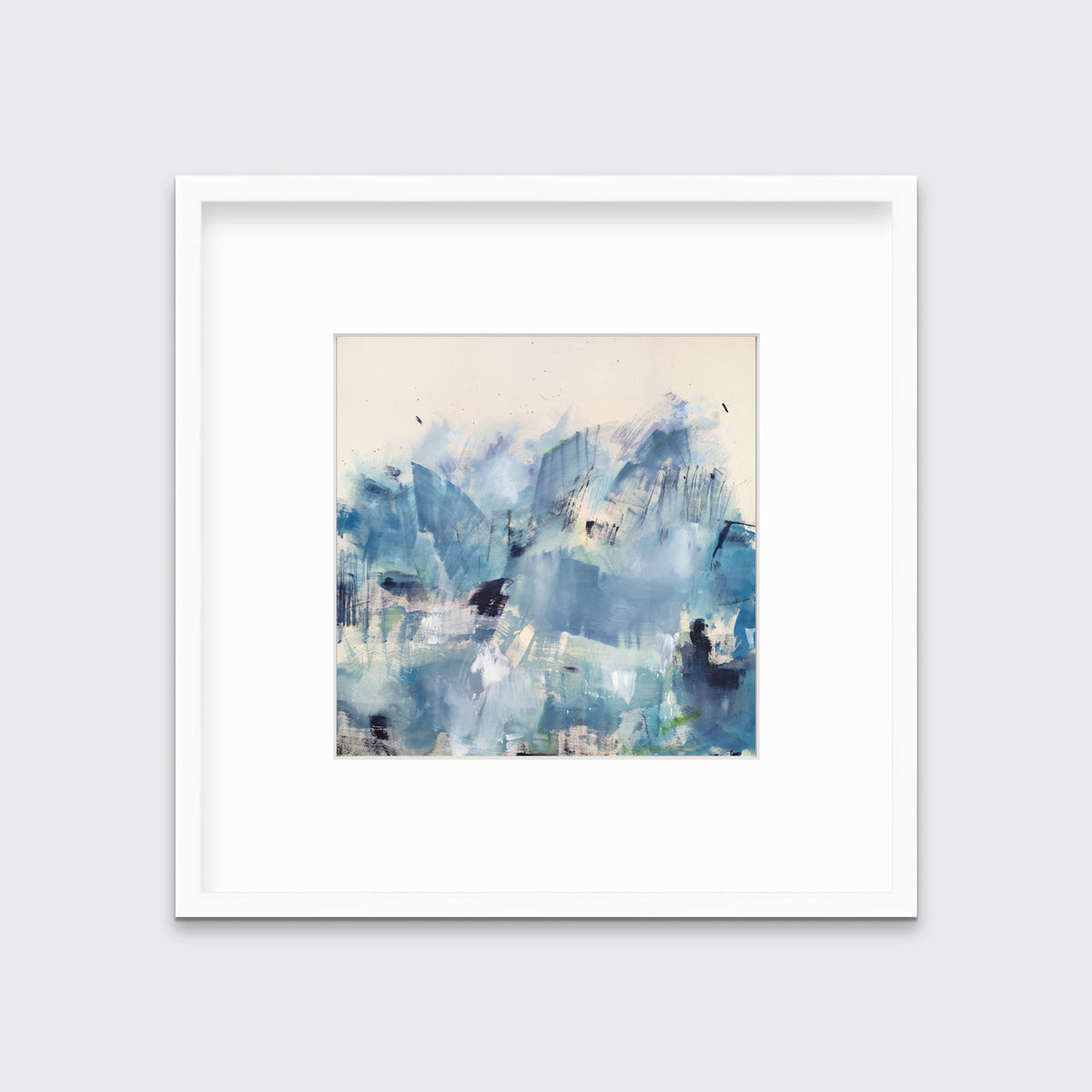 A blue and white abstract paper print framed in a white frame hangs on a white wall.