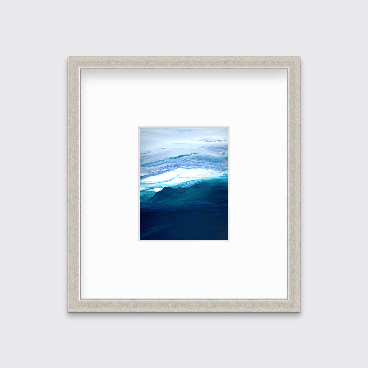 A blue, teal, lavender and white abstract print in a silver frame with a mat hangs on a white wall.