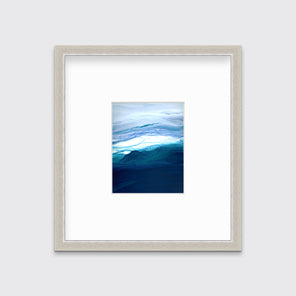 A blue, teal, lavender and white abstract print in a silver frame with a mat hangs on a white wall.