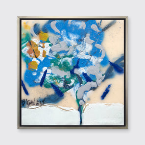 A blue, white, green and orange abstract print in a silver floater frame hangs on a white wall.