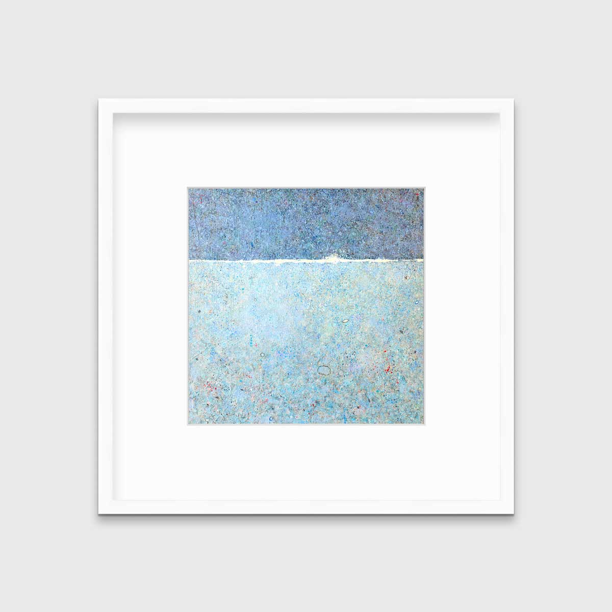 A blue abstract landscape print in a white frame with a mat hangs on a white wall.