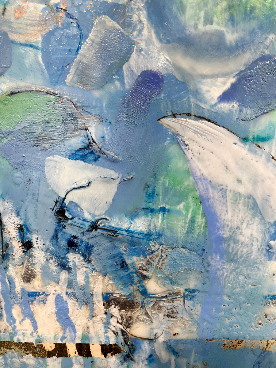 A detailed look at an encaustic painting with blue and turquoise marks. 