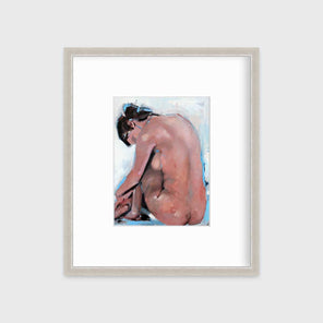 A contemporary seated figure facing away in a silver frame with a mat hangs on a white wall.