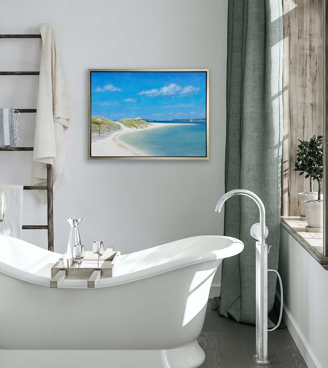 A blue, beige and light green contemporary seascape print in a silver floater frame hangs on a white wall above a vintage white bathtub, a ladder holding towels and a window with a sill holding two potted plants.