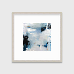 A blue and white abstract print in a silver frame with a mat hangs on a white wall.