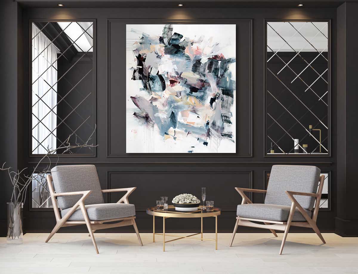Multi-colored cool toned abstract painting by Kelly Rossetti hangs on a charcoal grey wall with crown molding above a round glass table with gold details and two wood chairs with grey cushions. 