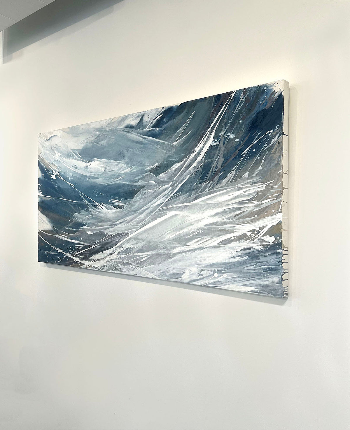 A white, blue, and grey abstract painting by Teodora Guererra hangs on a white wall, viewed from the right.