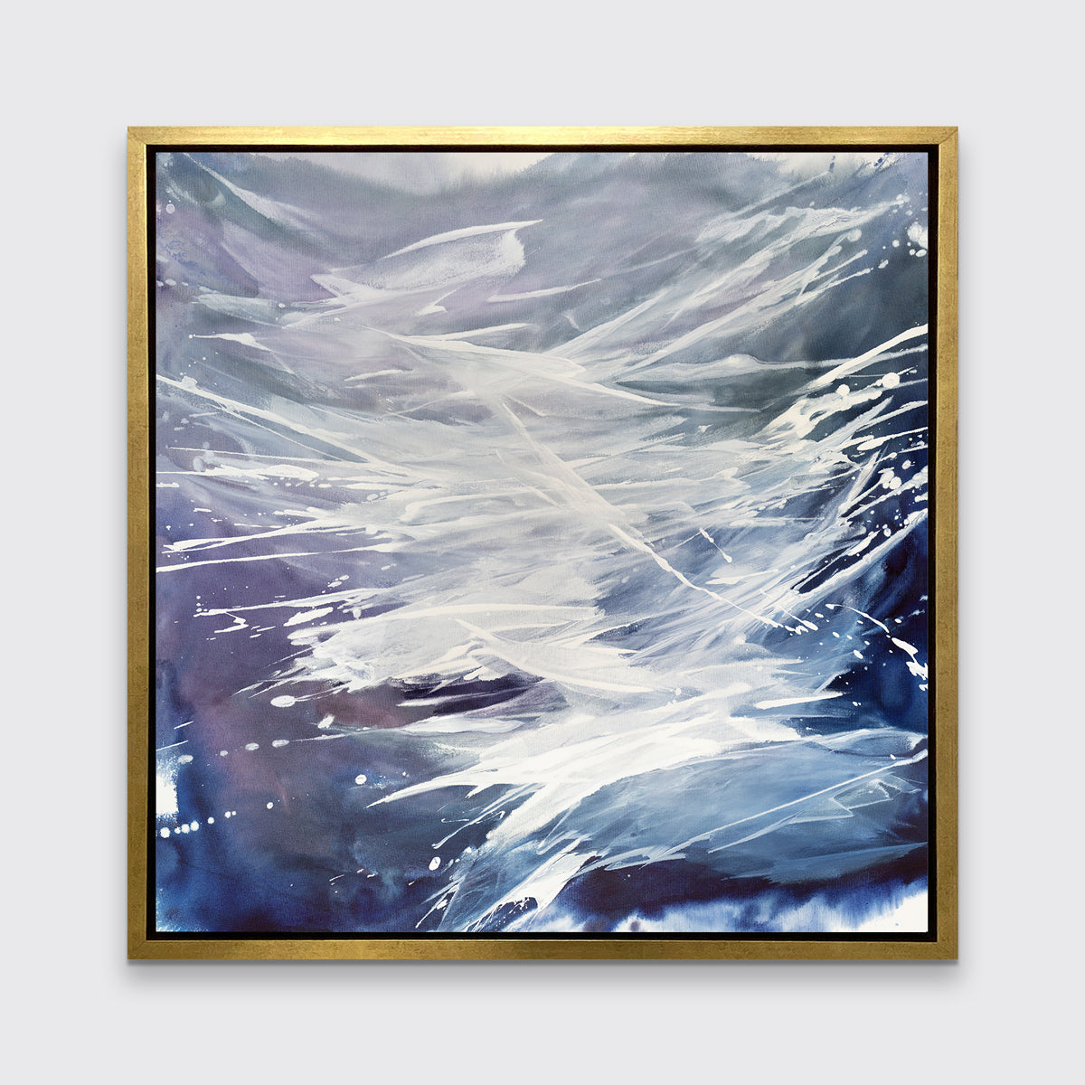 A purple, grey, white and blue abstract print in a gold floater frame hangs on a white wall.