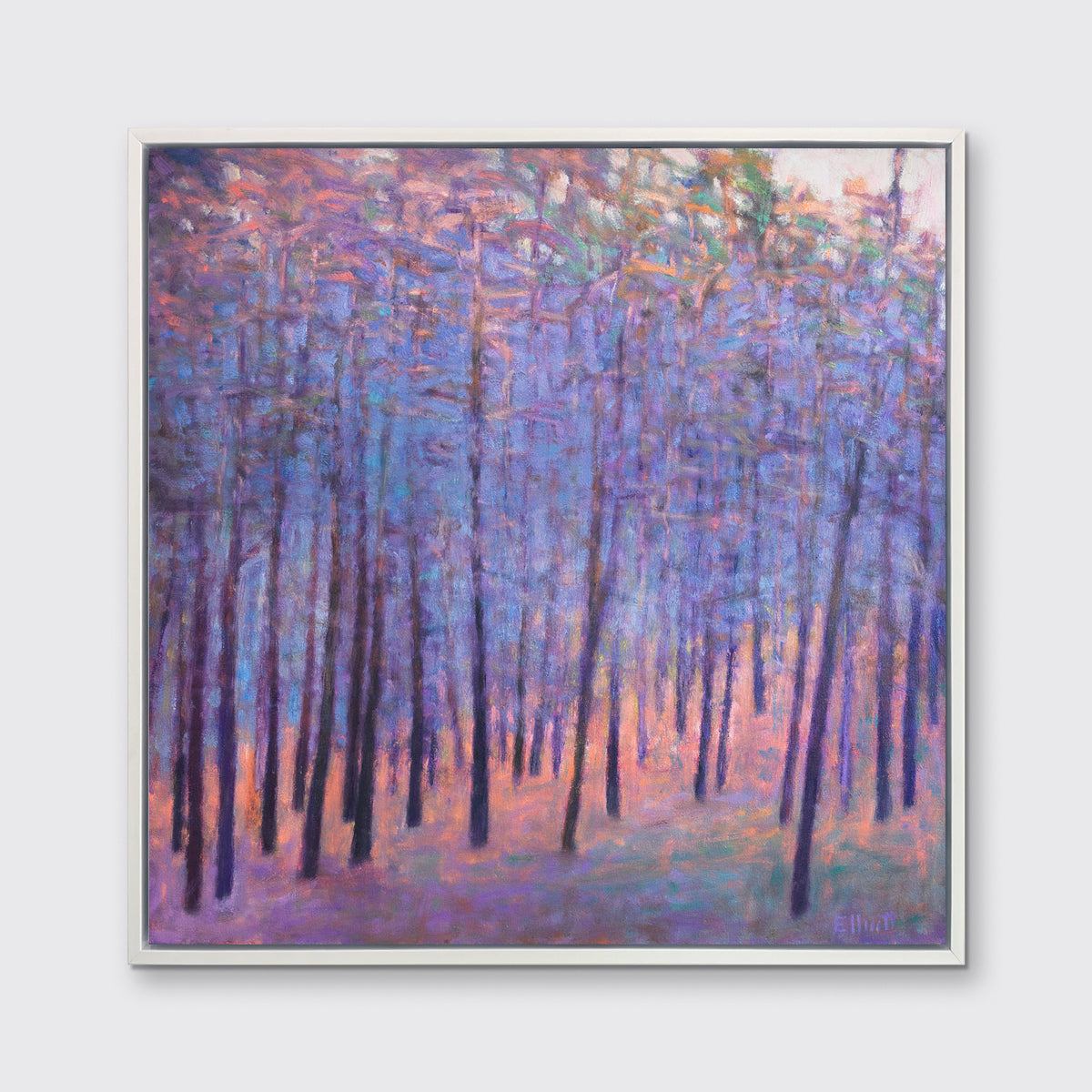 A blue and pink abstract tree landscape print in a white floater frame hangs on a white wall.