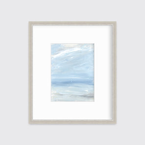 A white, blue and grey abstract seascape print in a silver frame with a mat hangs on a white wall.