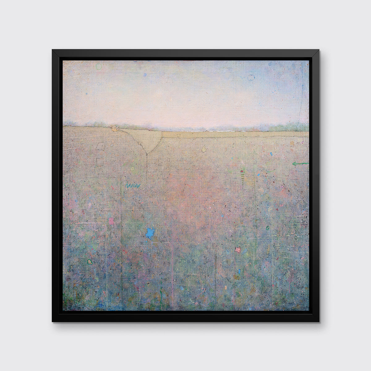 A green, pink and blue abstract landscape print in a black floater frame hangs on a white wall.
