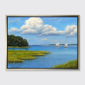 A realist contemporary seascape print with sailboats in a silver floater frame hangs on a white wall.