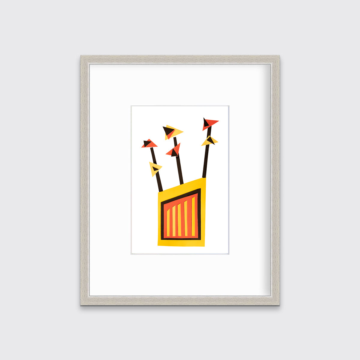 A red, yellow and black abstract collage print in a silver frame with a mat hangs on a white wall.