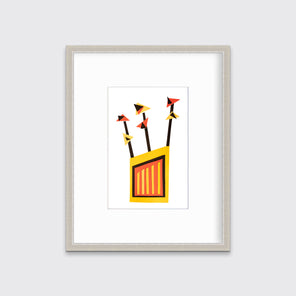 A red, yellow and black abstract collage print in a silver frame with a mat hangs on a white wall.